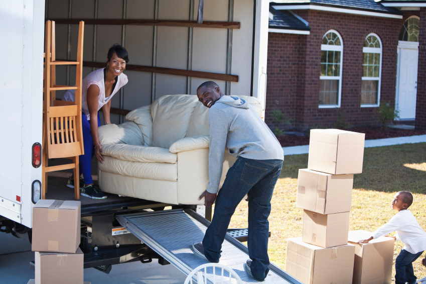 African American family moving house. Couple (30s) loading or unloading moving van.