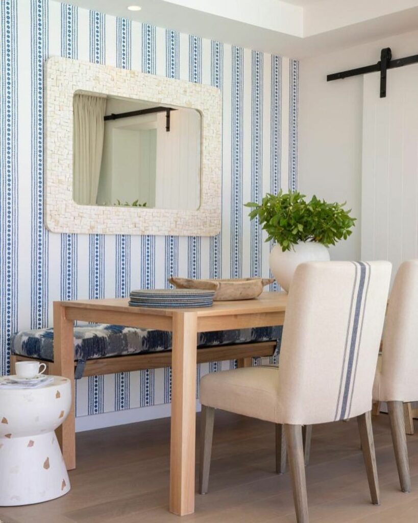 Dining area with blue striped wall paper and mirror 