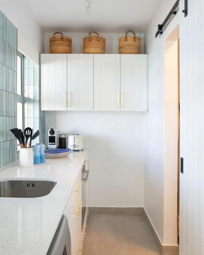 Kitchen with white cabinetry and blue wall tiles