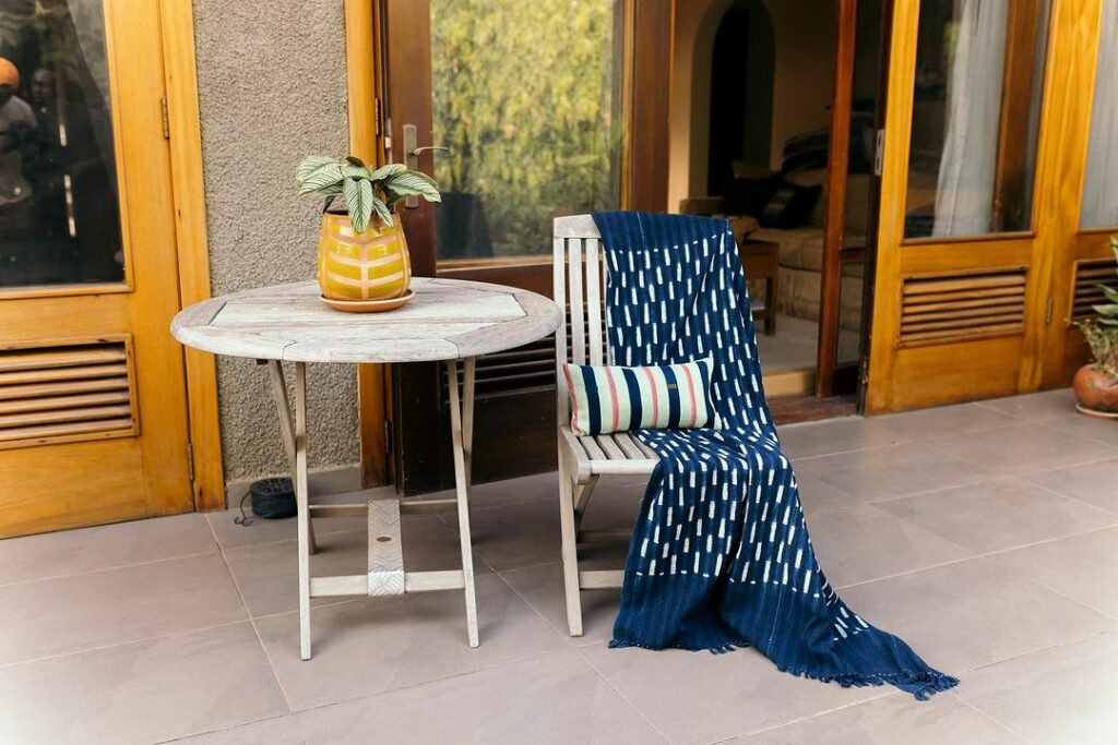 Blue 100% cotton afrocentric throw and Baoule cushion by Ghanaian homeware company, Daar Living on a chair in a house