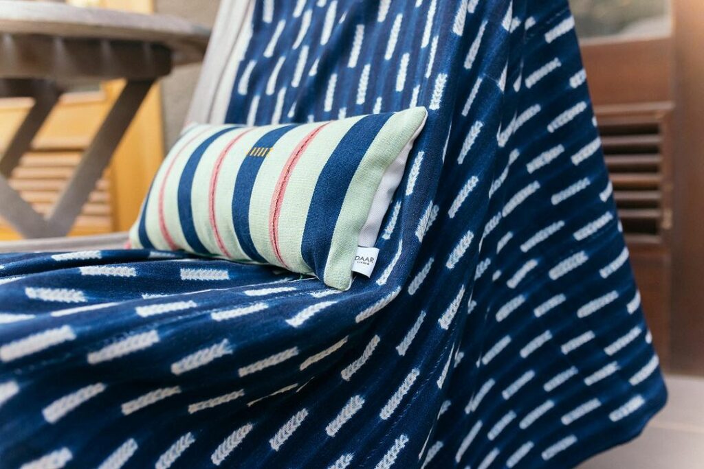 Blue 100% cotton afrocentric throw and cushion by Ghanaian homeware company, Daar Living on a chair in a house