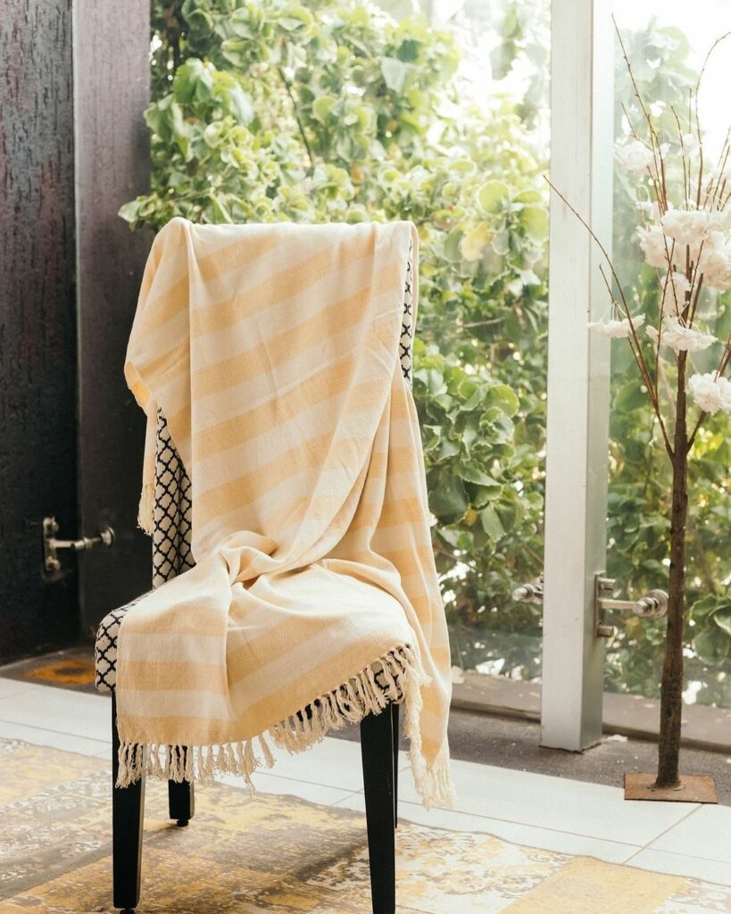 Stripe patterned throw by Ghanaian homeware company, Daar Living on a chair in a house