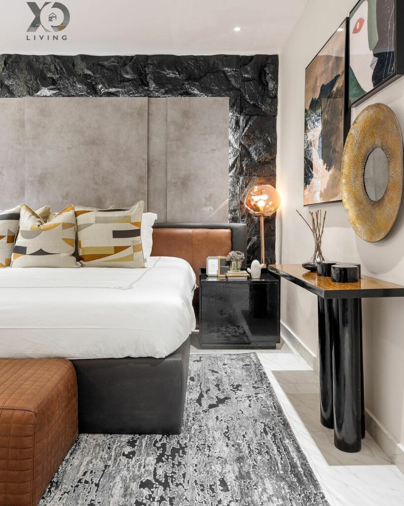 A view of the Master bedroom by Xo Living showing the lush decor and furnishing layered on the rock feature wall.