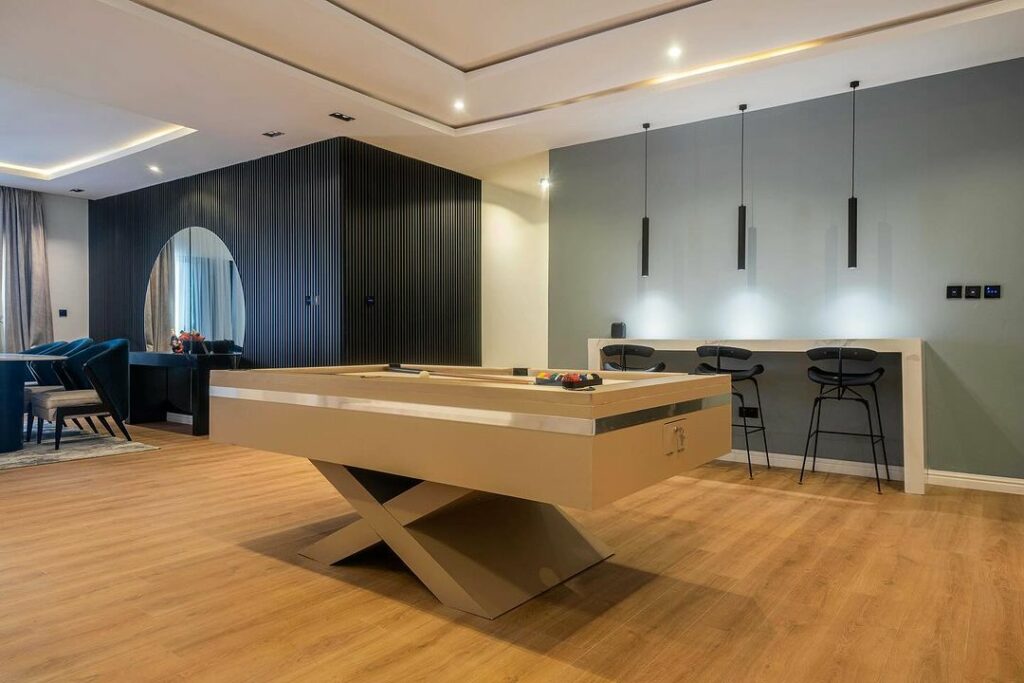 A view of the serene modern living room in in BIllard table with bar seating and three drop down lights.