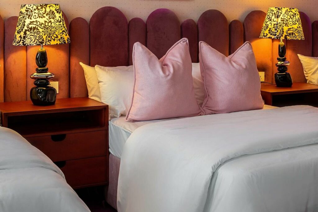 Pink-themed sleeping area with yellow bedside lamps.