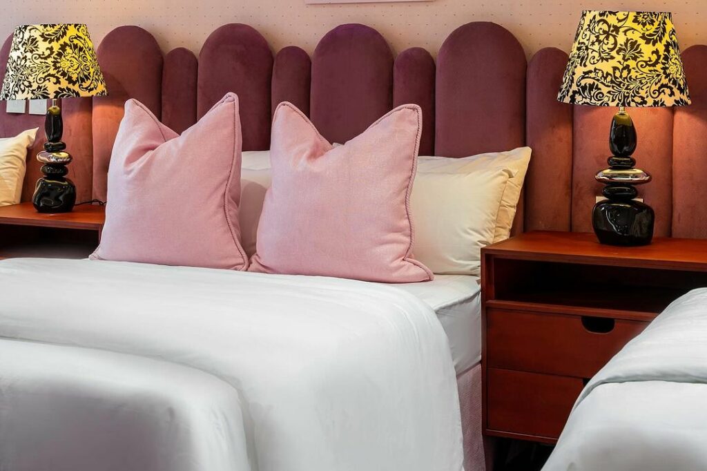 Pink-themed sleeping area with yellow bedside lamps.