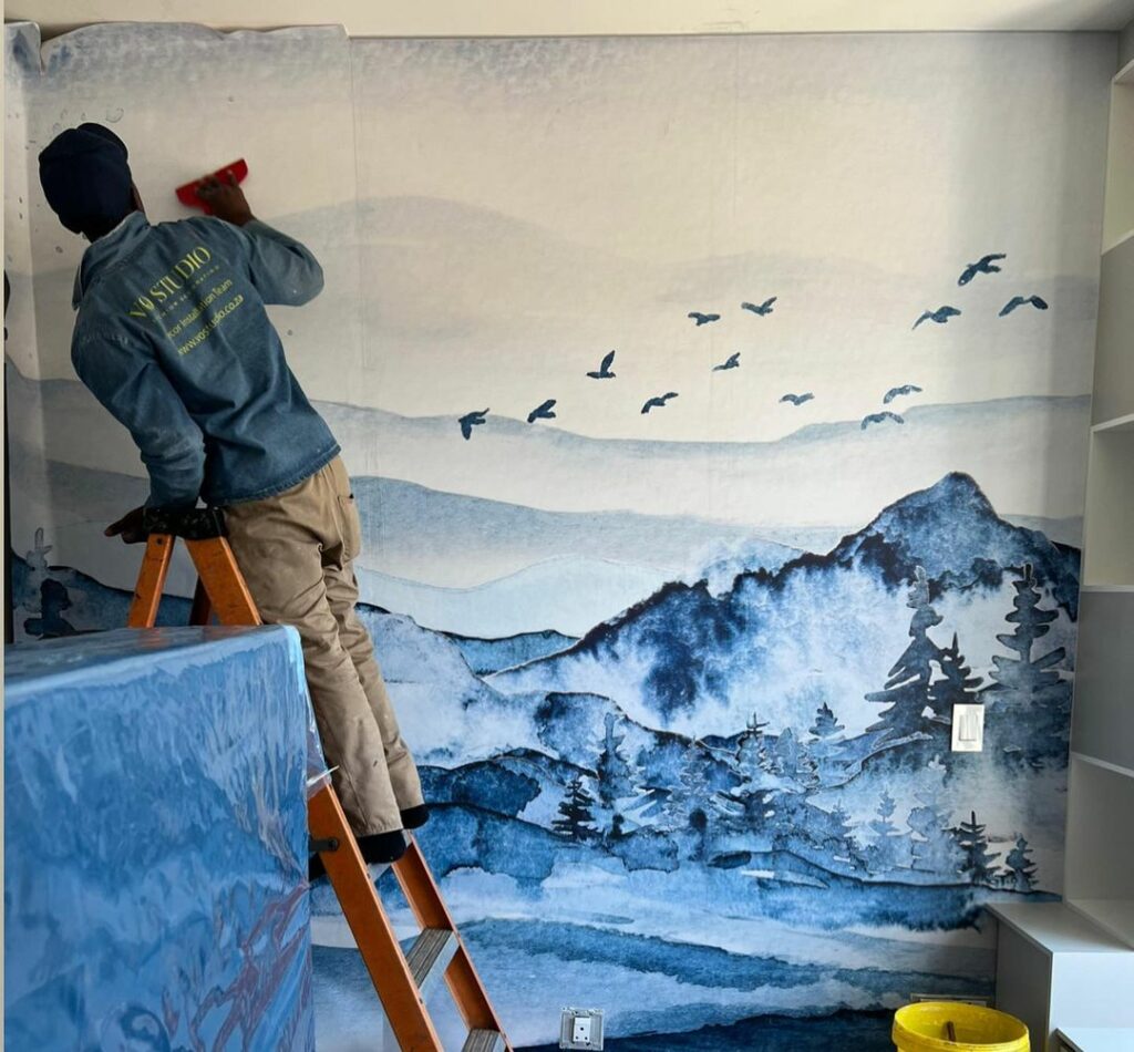 Man applying wall mural in kids bedroom