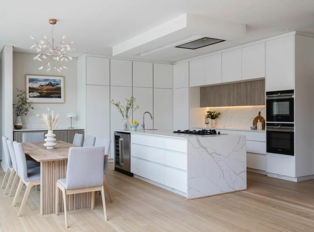 Modern white kitchen with dining area in Home V in South Africa.