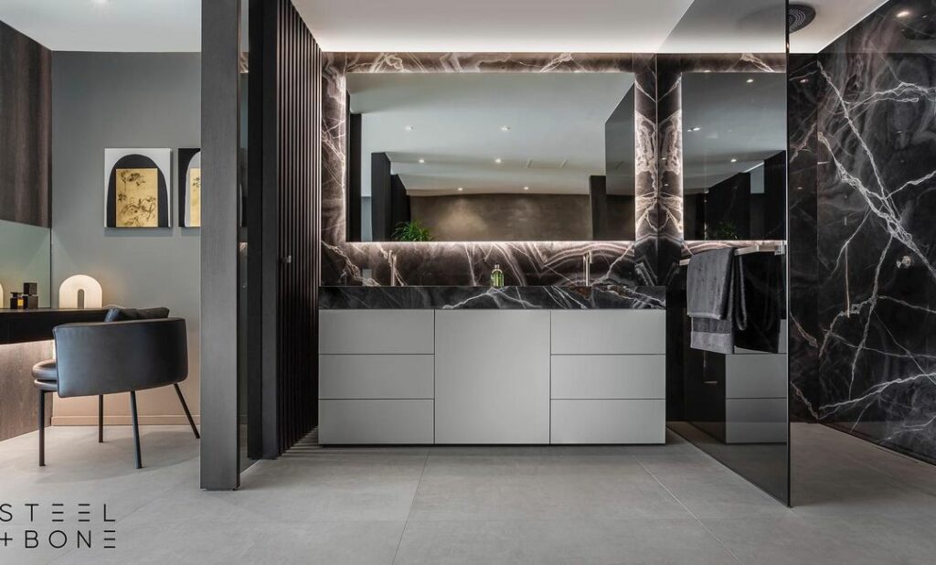 Dark-themed bathroom and dresser in the Luxurious interior by steel and bone in South Africa.
