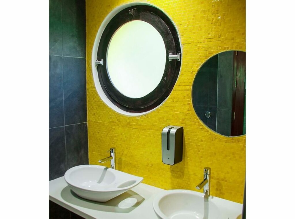 Bathroom with yellow accent wall and round window.