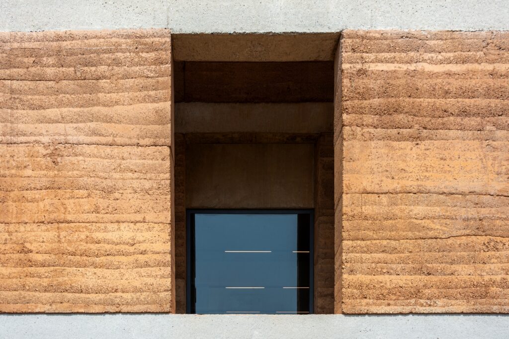 South-facing windows shaded by double rammed earth facade.