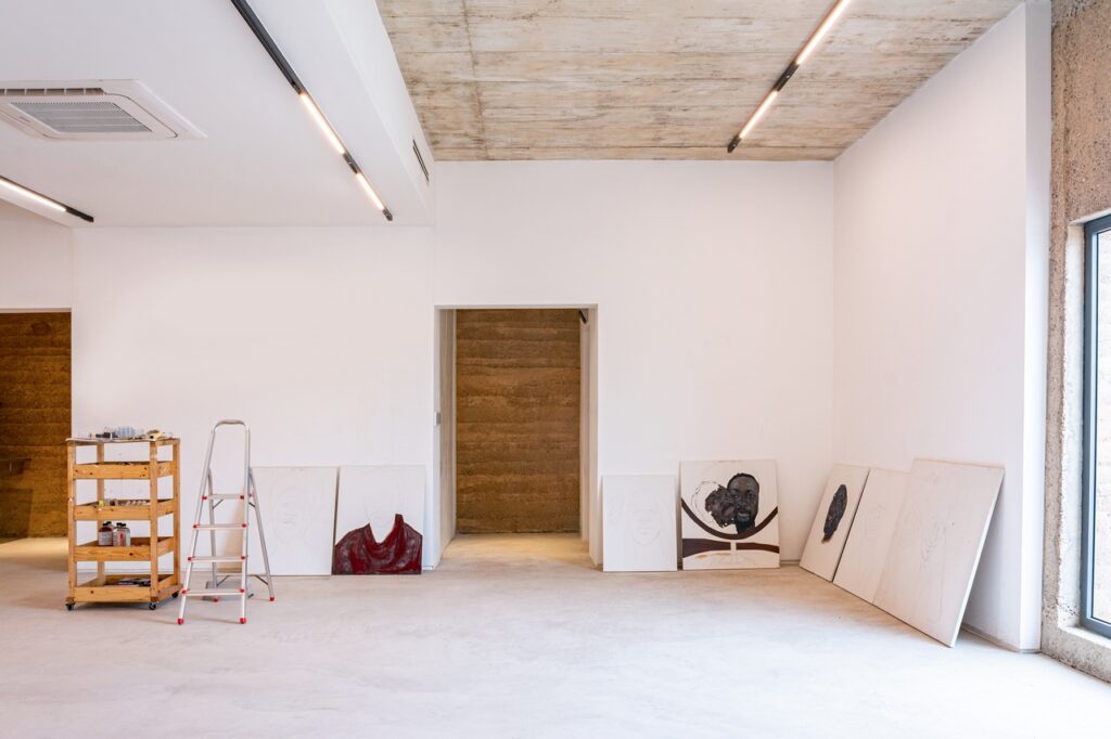 Interior featuring white walls, expose concrete and rammed earth.