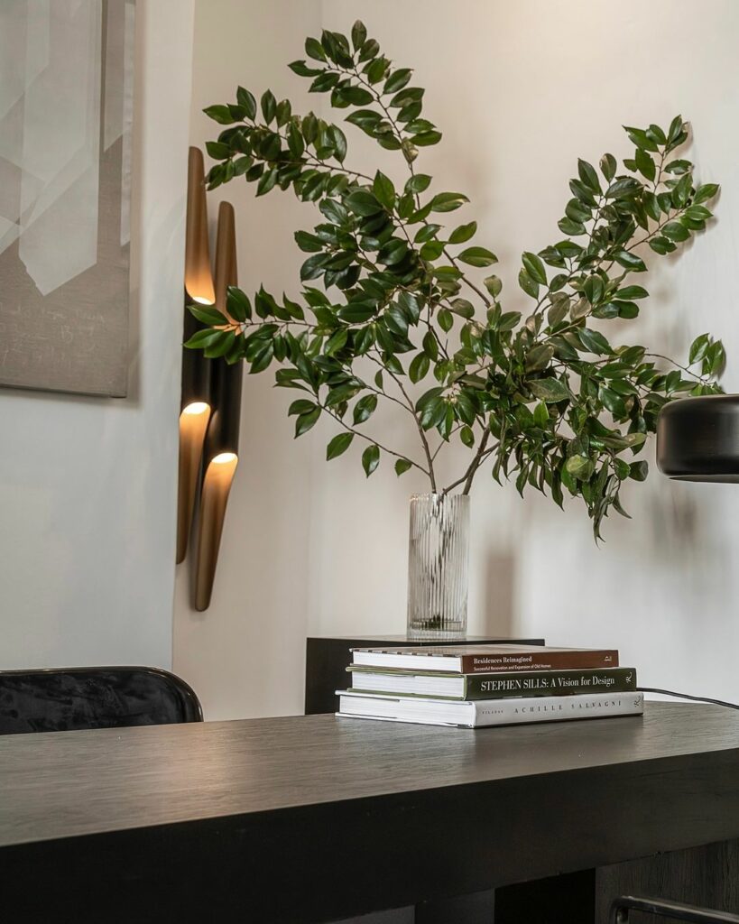 Modern table with indoor plant and stylish sconce.