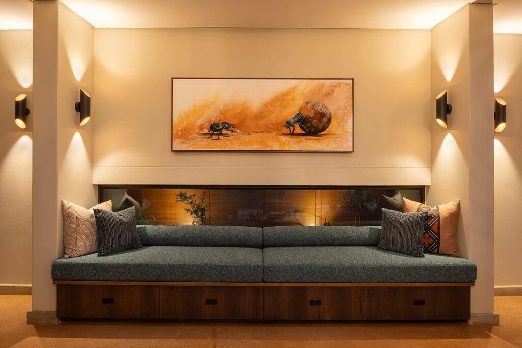 Modern lounge area at Melote House with a teal sofa, abstract orange artwork on the wall, and mood lighting in wall sconces.