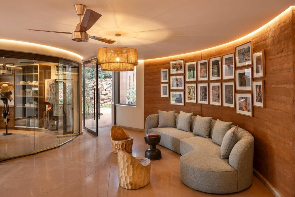 A cozy room featuring a curved sofa, gallery wall with multiple framed photos, a glass partition, and warm lighting. stylish ceiling fan and wooden floors complement the ambiance.