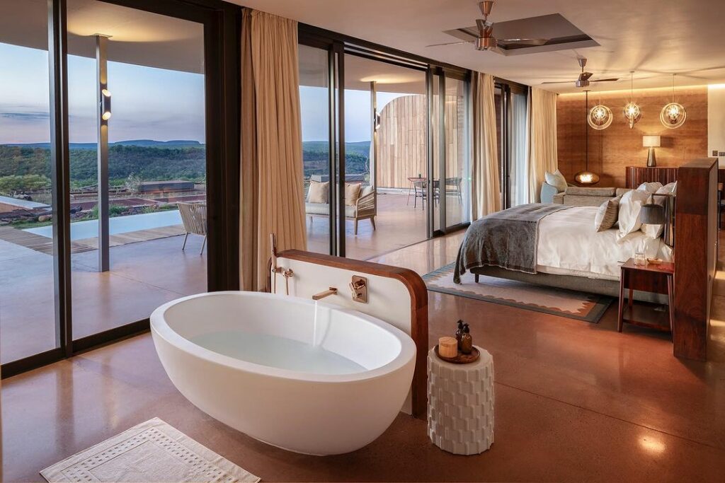 A luxurious bedroom in Melote House featuring a large bed with cozy seating and a free standing bath tub.