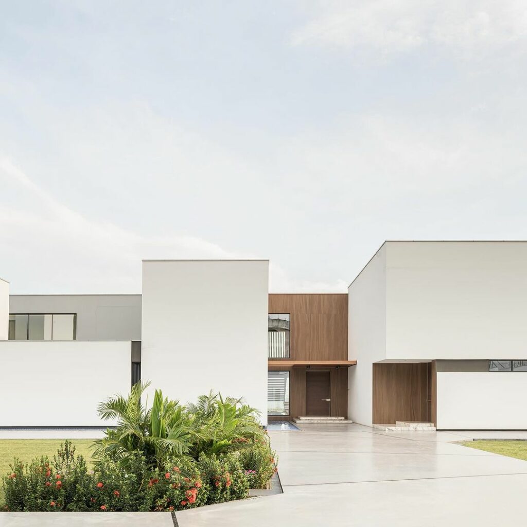 Contemporary modern home in Guinea with white facade and lush green lawn.