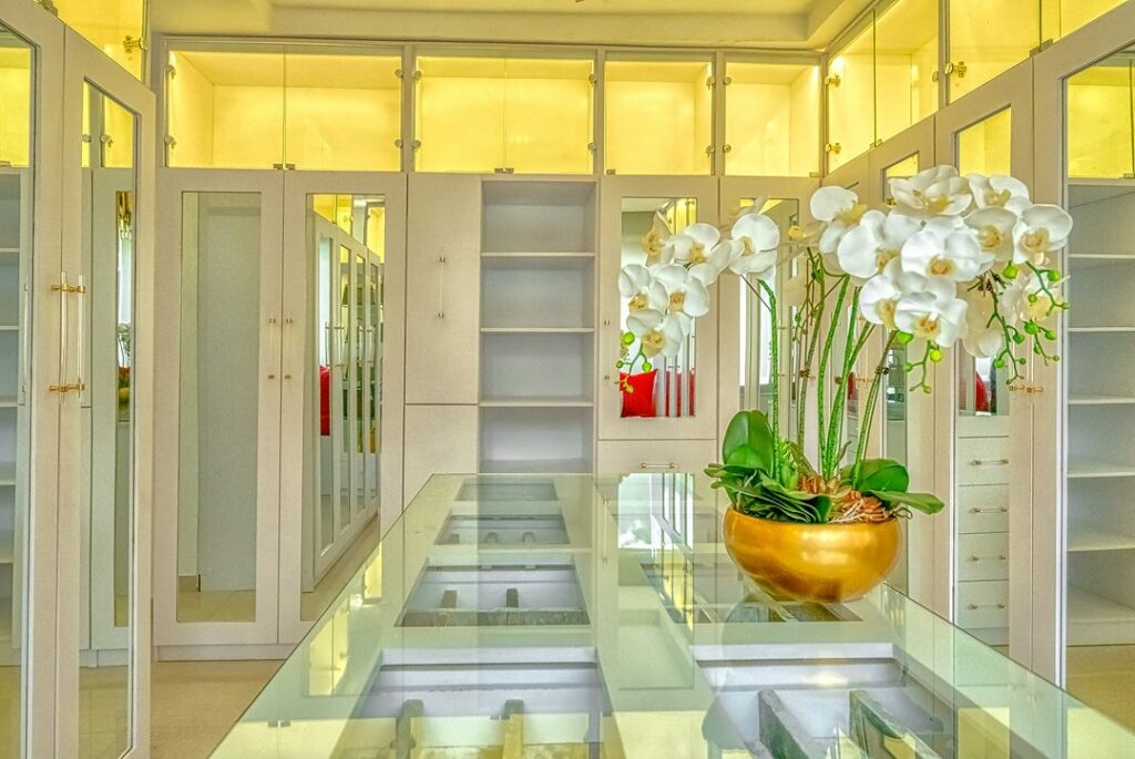 An organized walk-in closet featuring a vase of orchids