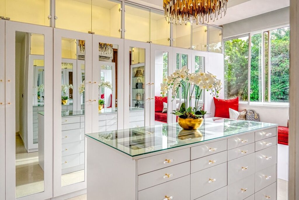 A luxurious walk-in closet adorned with a sparkling chandelier and elegant mirrors.
