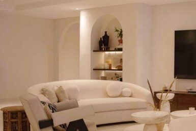 A modern living room with white furniture and a flat screen TV.