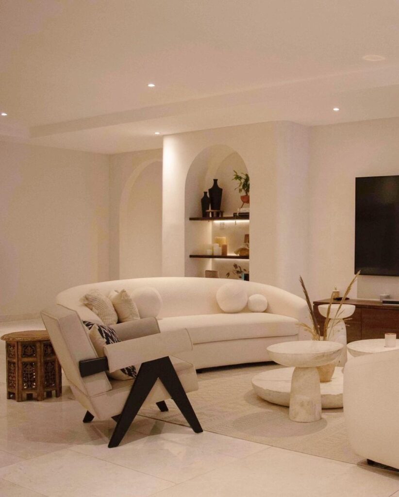 A modern living room with white furniture and a flat screen TV.