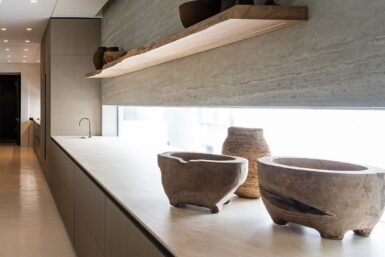 A spacious kitchen with live-edge shelving and a sink, providing ample storage and a functional workspace.