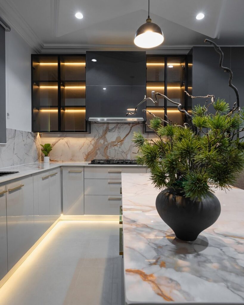 A contemporary kitchen featuring calcatta marble countertops and stylish lighting.