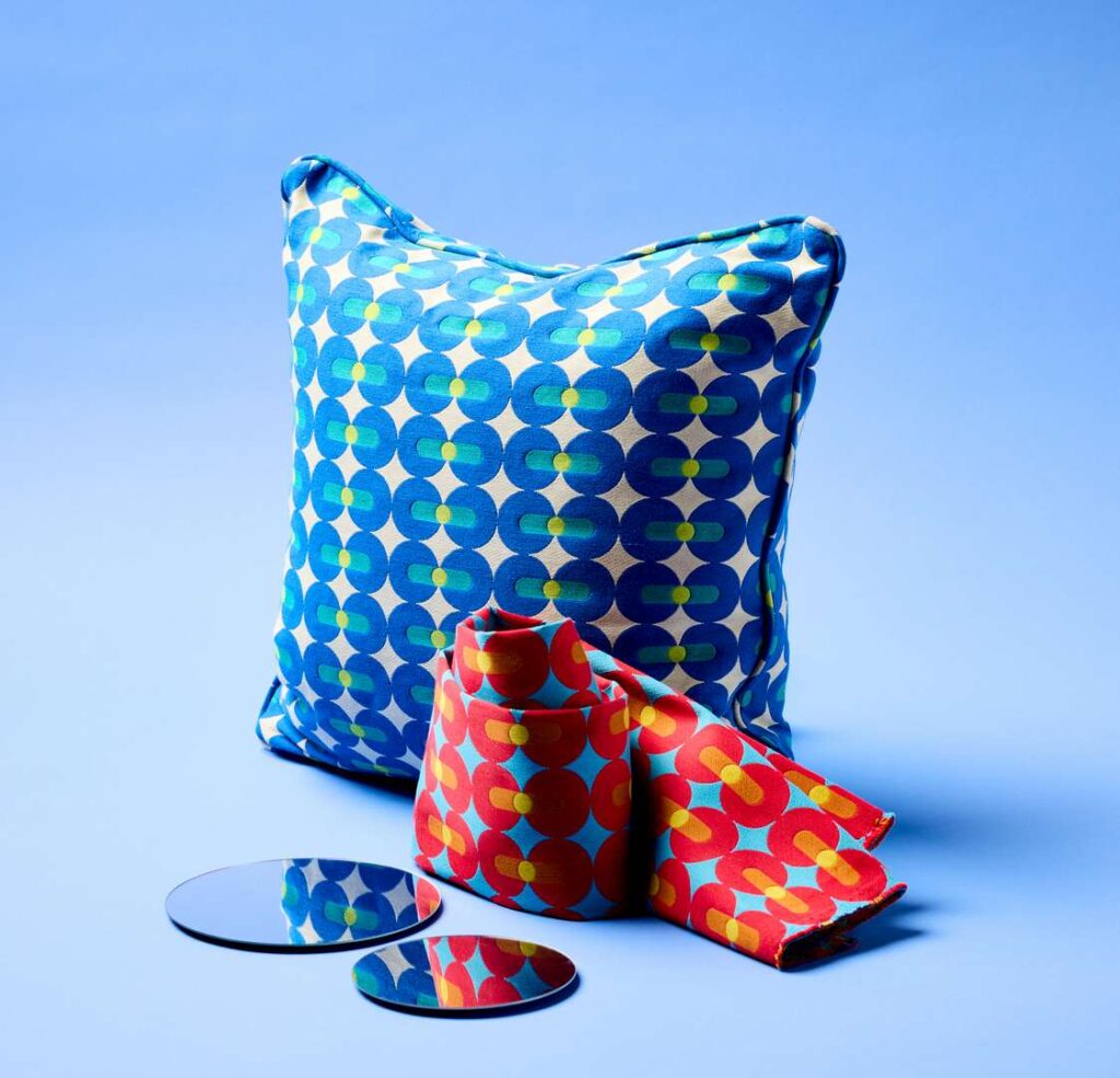 A blue pillow with a mirror and a matching blue and red scarf lying on top.