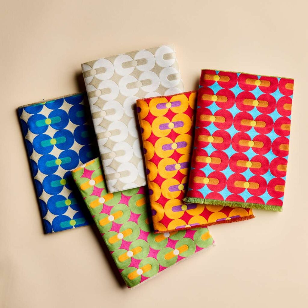 Four colorful paper napkins with geometric designs, perfect for adding a pop of color to any table setting.