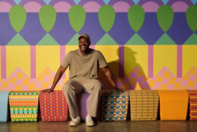 A man sitting on a colorful bench in front of a vibrant wall, enjoying a sunny day in the park.