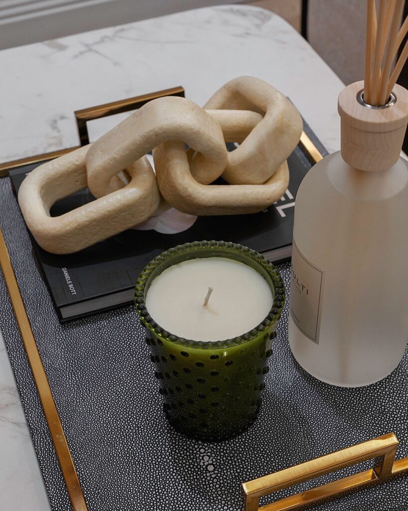 A tray holding a candle, a bottle of perfume, and a book, creating a serene and cozy ambiance.