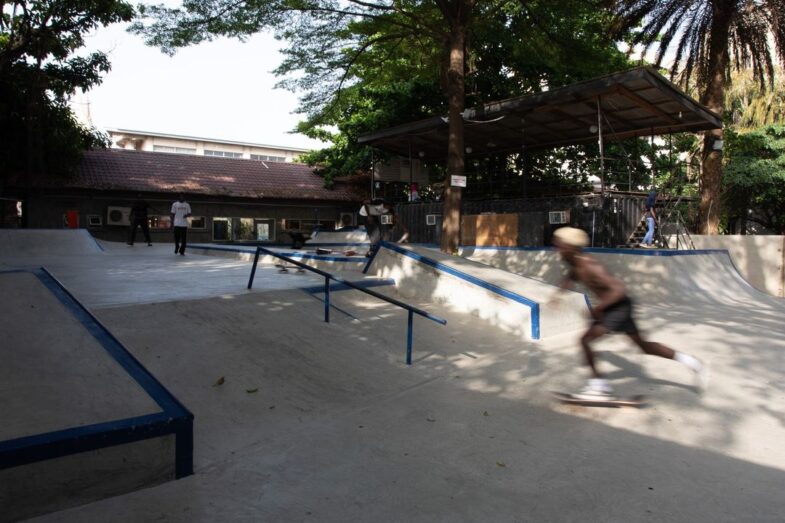 Skatepark surrounded by trees casting shadows and providing shade.