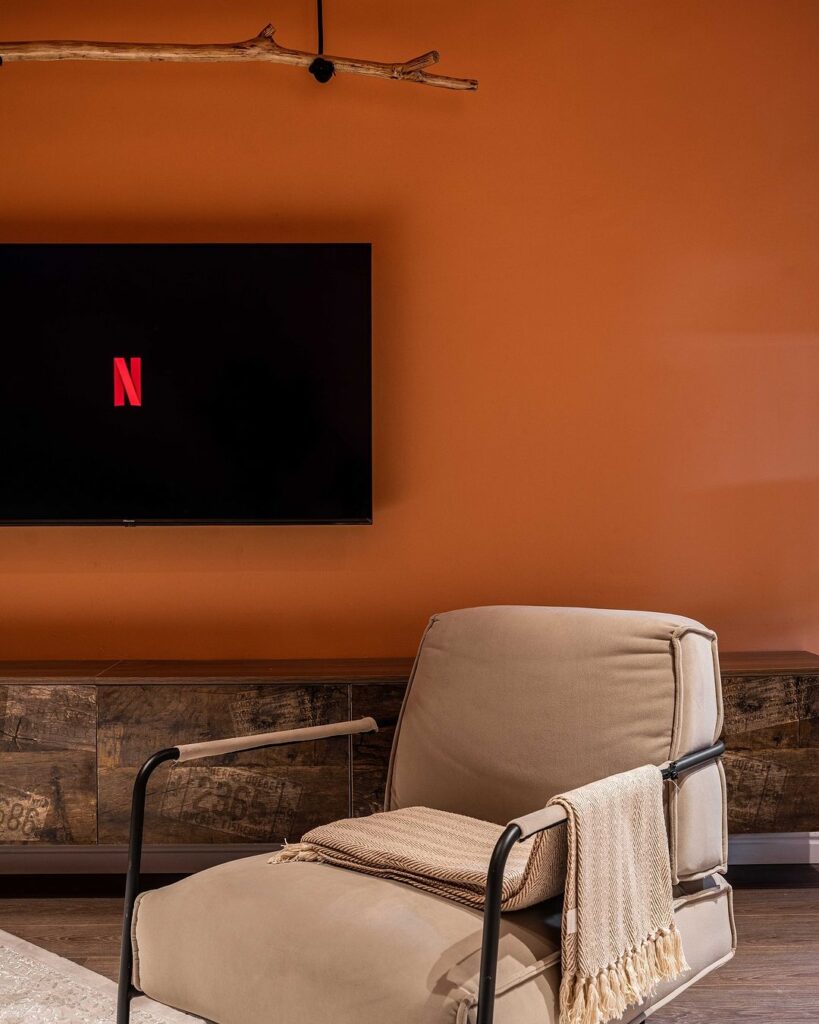 A TV mounted on a wall in front of a chair, creating a cozy entertainment setup.