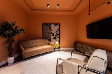 A cozy living room with vibrant orange walls and a comfortable couch.