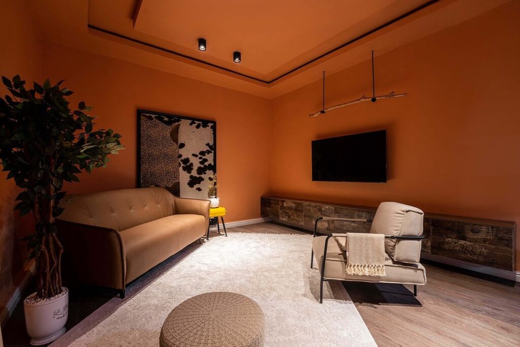 A cozy living room with vibrant orange walls and a comfortable couch.