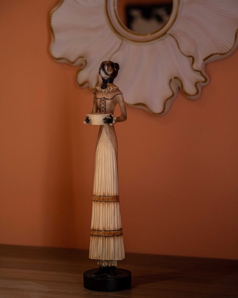 A woman figurine holding a basket on a wooden stand.