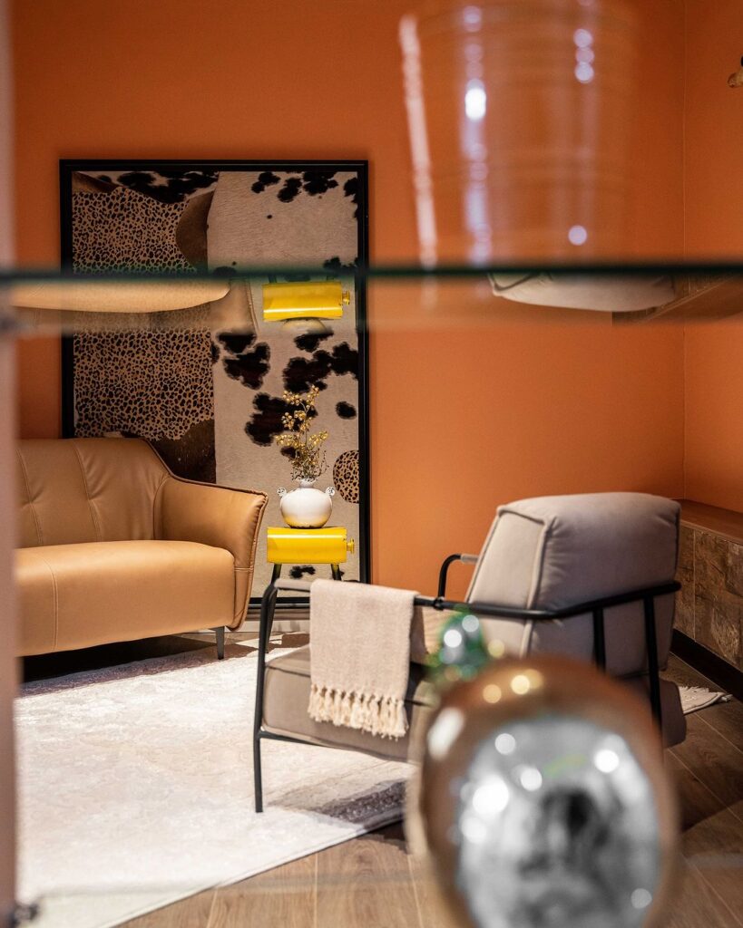 1. Living room with orange walls, glass shelf, and cozy atmosphere.