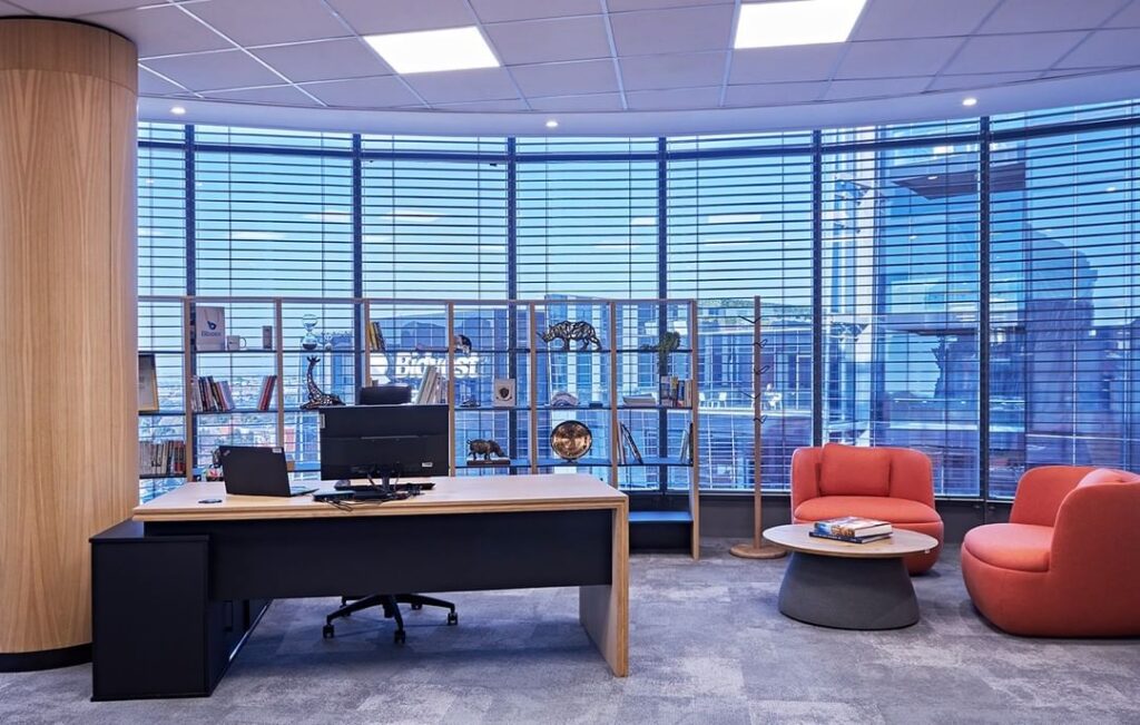 Office space with wooden executive desk, two single sofas and one coffee table with a grand view of the city.