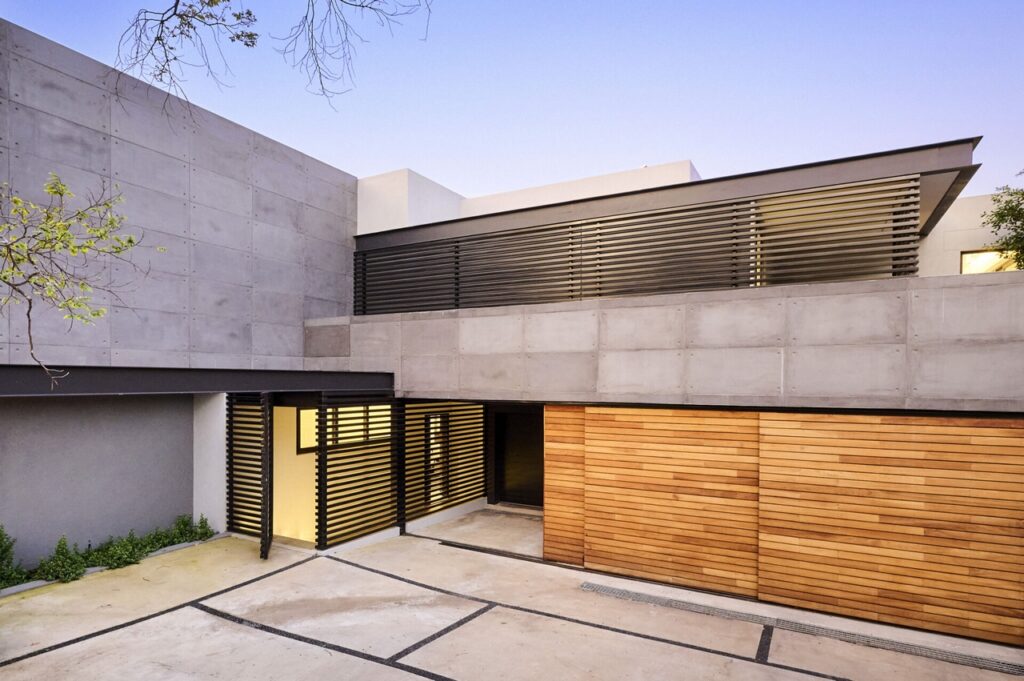 A contemporary concrete house featuring stylish wooden garage doors and windows.