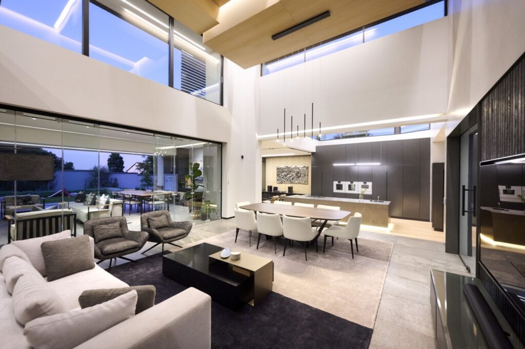 A contemporary double volume living room with expansive windows and a dining area.
