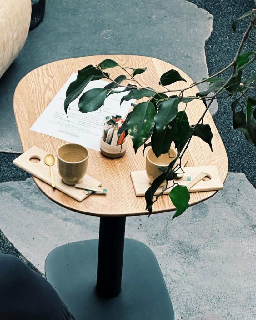 A table with a plant and a wooden cup on it.