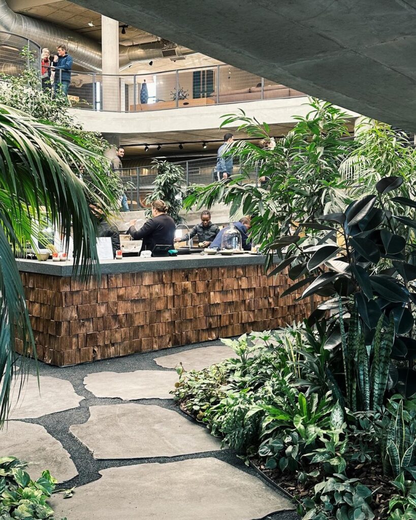 Atrium with lush plants surrounding a central bar, creating a serene and inviting atmosphere.