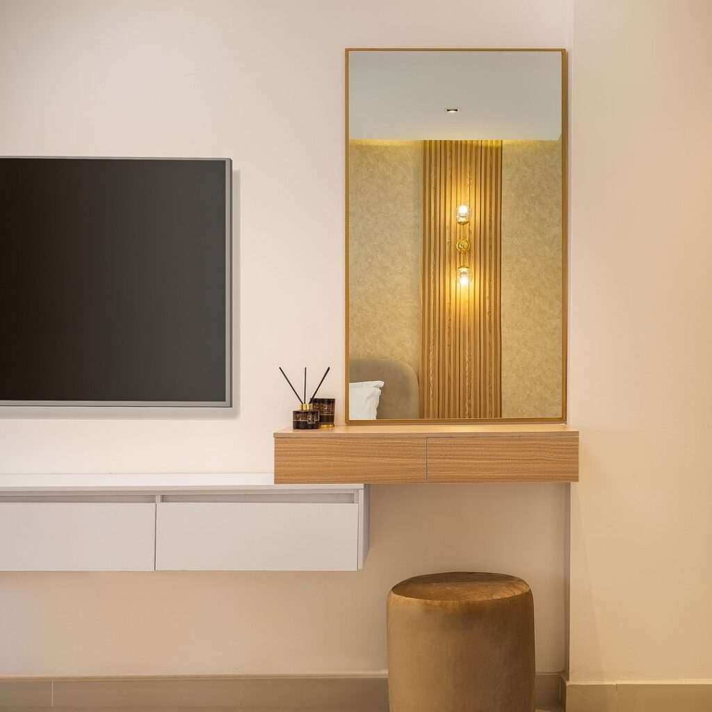 Contemporary bedroom TV wall with modern dresser and mirror.