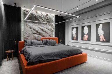 Statement bedroom with orange bedframe and rocky textured wall.