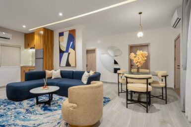 Open plan living room with blue accents and a kitchenette